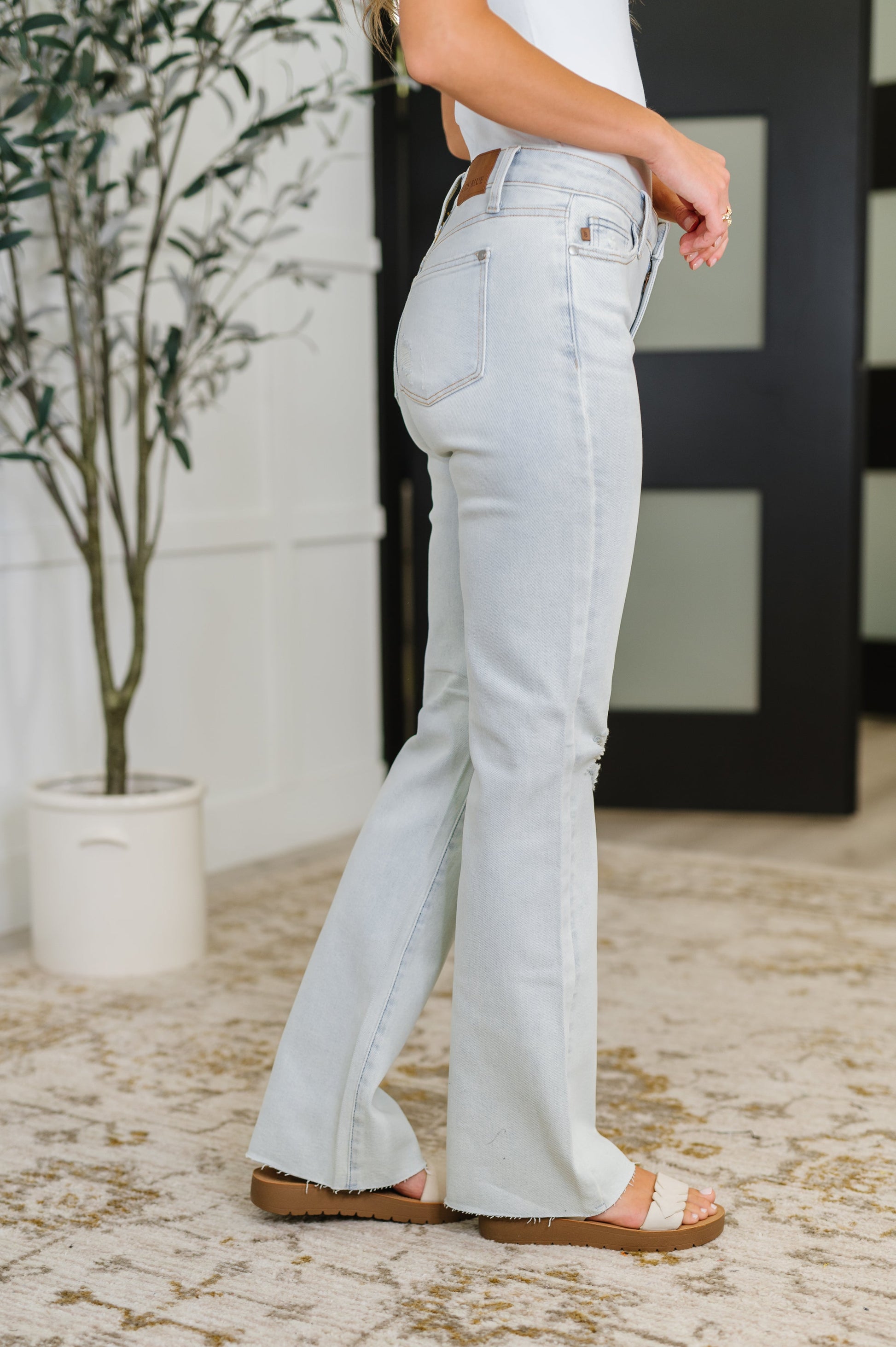 Light blue jeans worn by a person indoors with a plant in the background