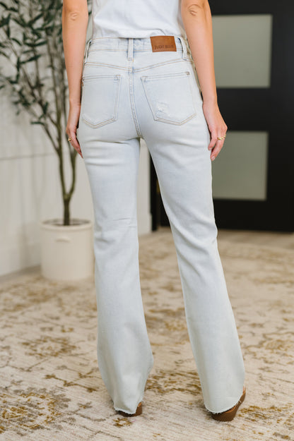 Light blue jeans worn by a person indoors with a plant and rug in the background