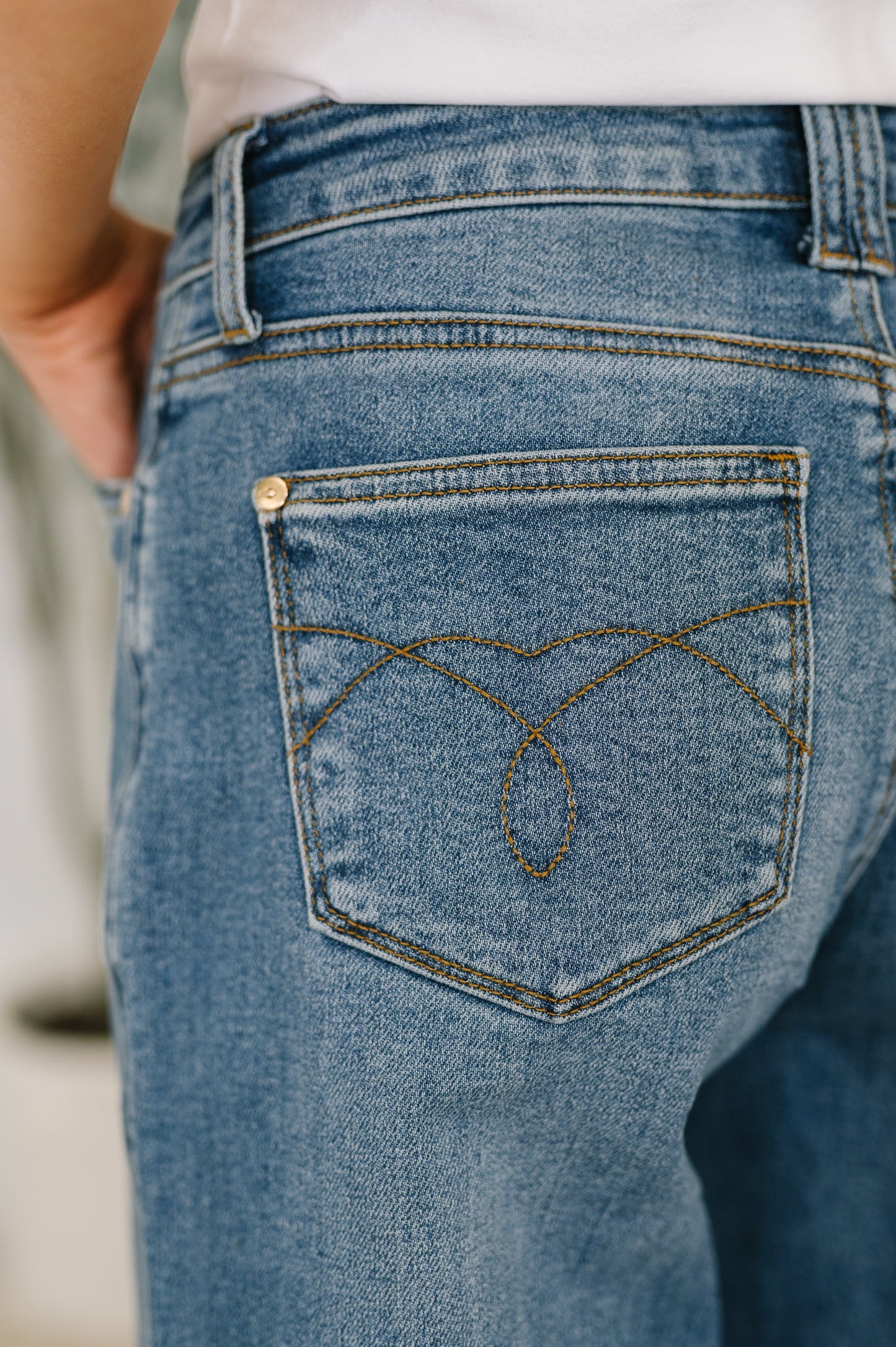 Close-up of blue jeans with a brand logo on the back pocket.