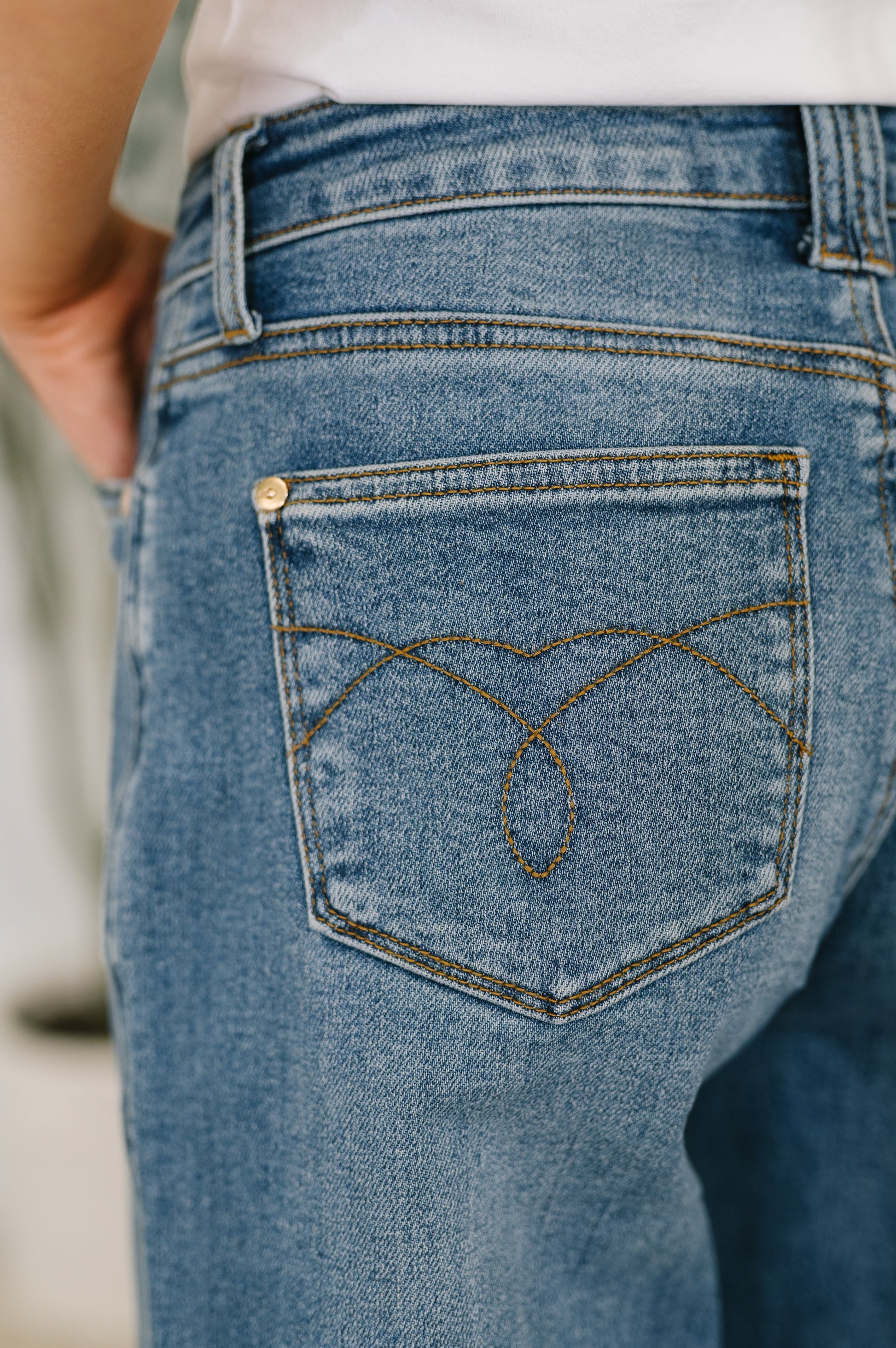 Close-up of blue jeans with a brand logo on the back pocket.