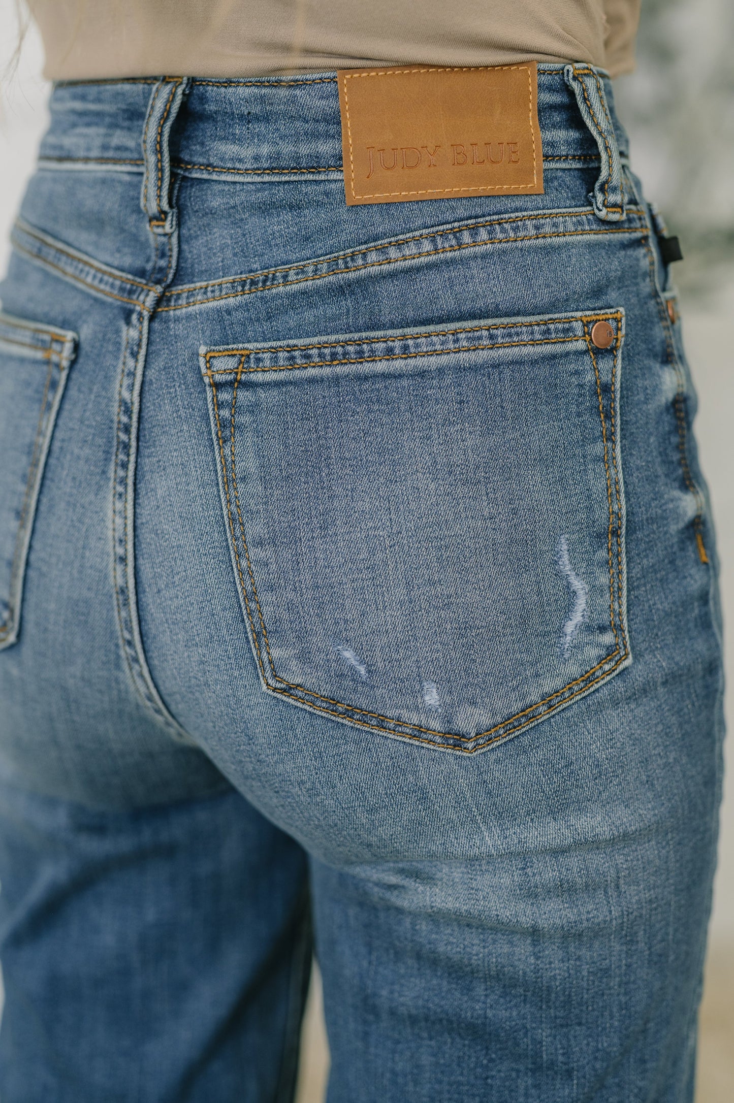 Close-up of blue jeans with a brand label on the back pocket.