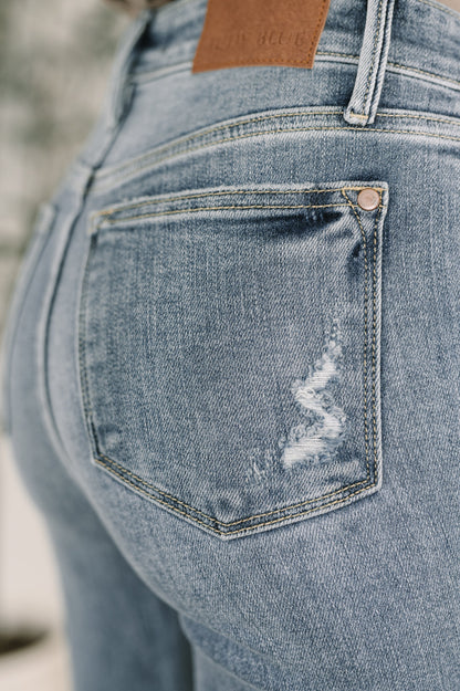 Close-up of a blue denim pocket with a brand logo, blurred background